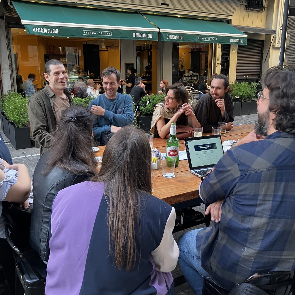 En un grupo sentado alrededor de la mesa de café la diaria, una persona presenta su proyecto mientras el resto escucha.